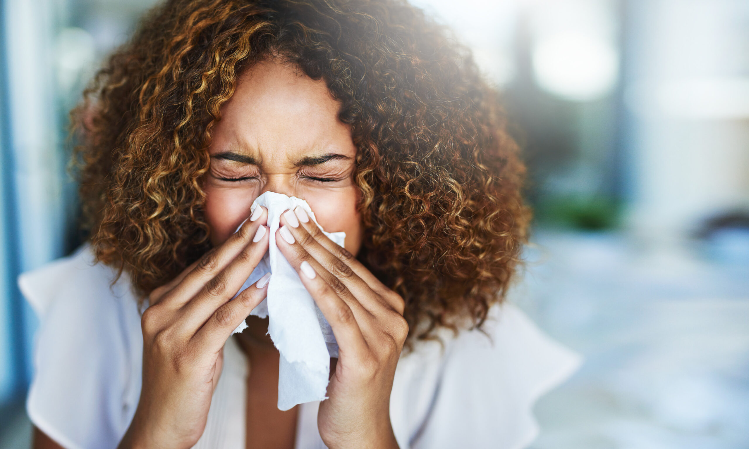 Woman Sneezing into Tissue